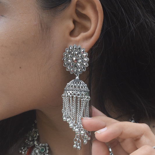 Close-up of a woman wearing silver earrings with a blurred natural background